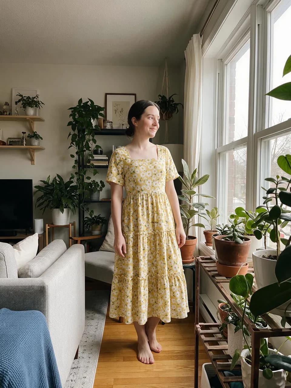 Woman by a sunny window wearing a yellow floral midi dress taken from a mannequin product photo