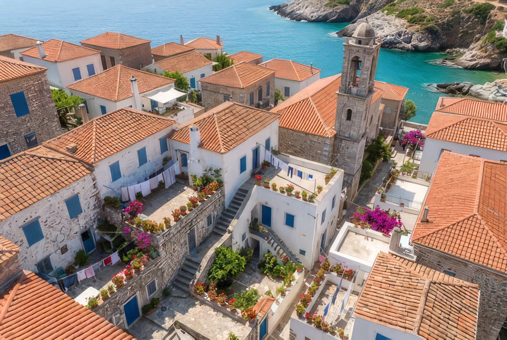 An aerial photo of a white hillside village with terracotta roofs above a turquoise sea, upscaled 4×