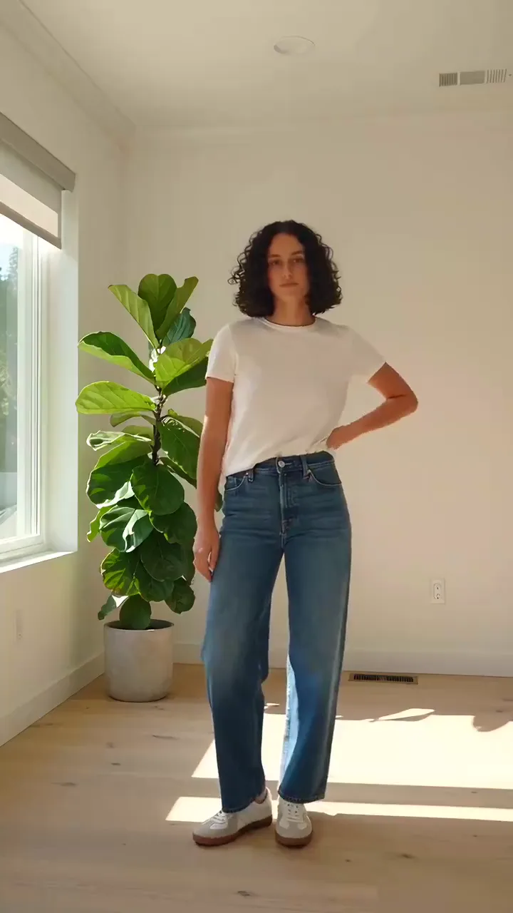 The original clip: a woman doing a fit check in a white t-shirt and jeans in a sunlit living room